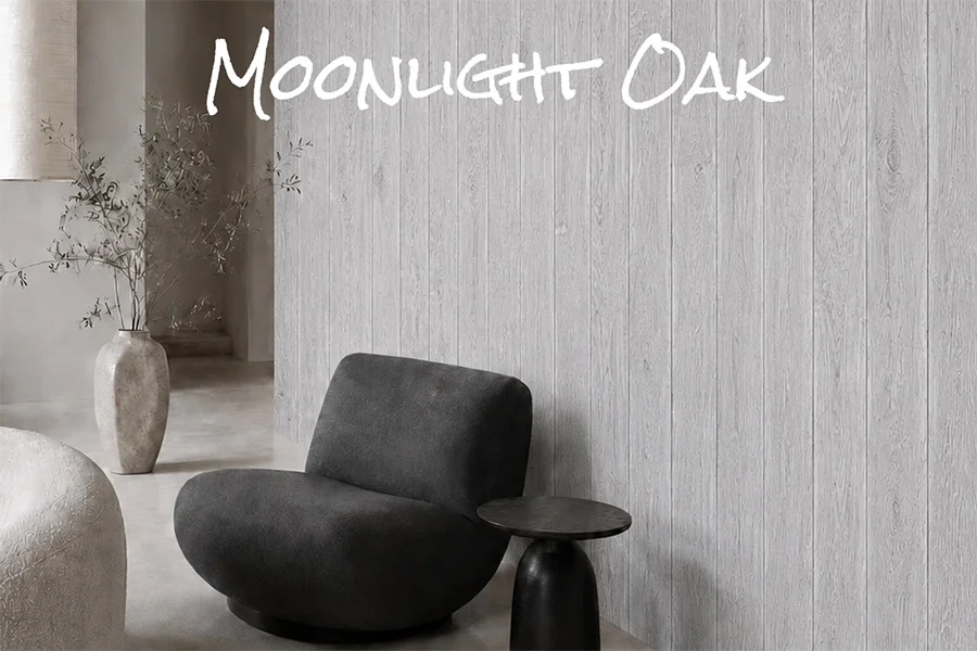 Czarny fotel i okrągły stolik przy jasnoszarej ścianie z desek dębowych moonlight, z nazwą wykończenia na kadrze